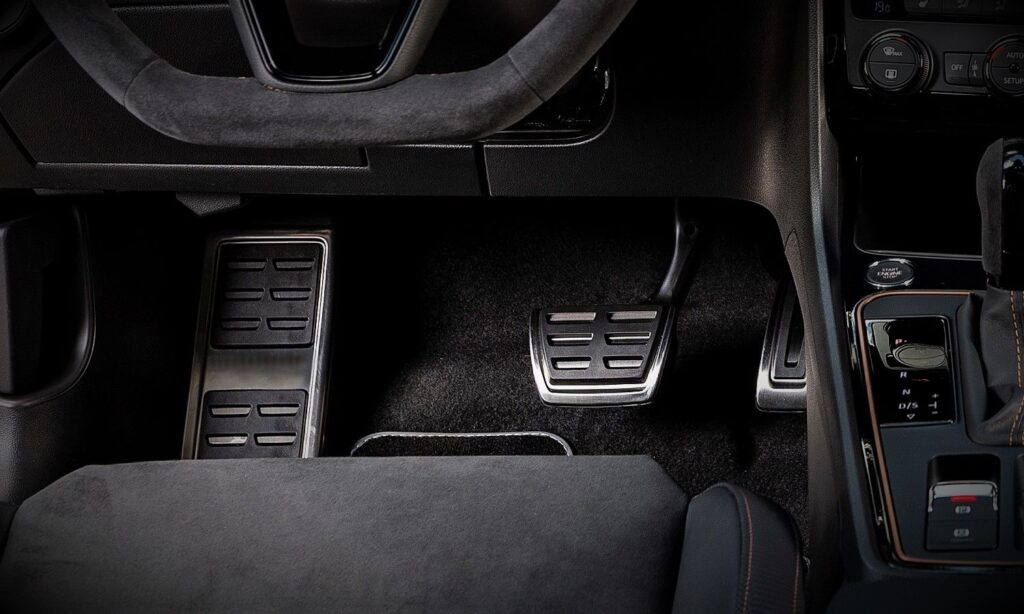 Interior del vehículo enfocado en el área de los pedales, mostrando el pedal de freno y acelerador con acentos metálicos.