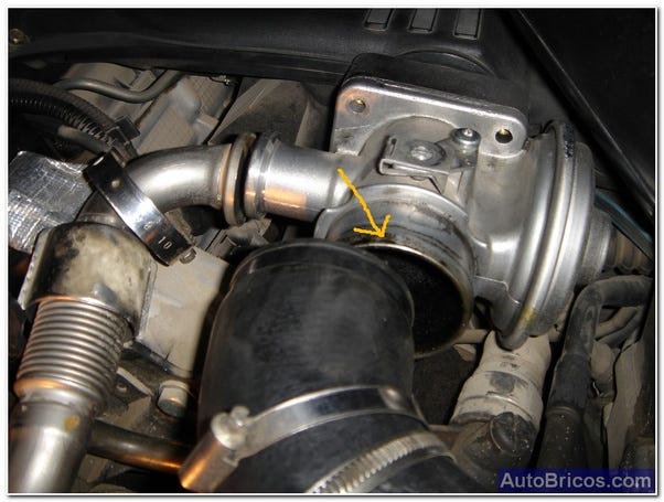 LA imagen muestra un cuerpo de válvula EGR al que llega el tubo de admisión. Tiene señalado el borde del cuerpo de válvula por la parte que hará contacto con el tubo. El tubo es de goma negra y tiene las bridas desplazadas para que no se caigan al aflojarlas. El cuerpo de EGR es de metal gris.