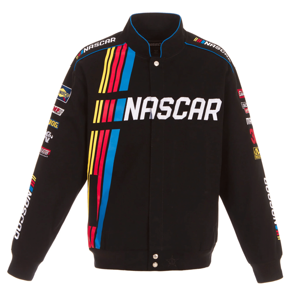 Imagen de una chaqueta negra de NASCAR con cremallera frontal. El cuello es azul y hay franjas coloridas en azul, rojo y amarillo en la parte delantera que forman la palabra ‘NASCAR’. Hay varios parches de patrocinadores en ambas mangas y en el área del pecho. Los puños y la cintura parecen ser de tejido elástico y acanalado.