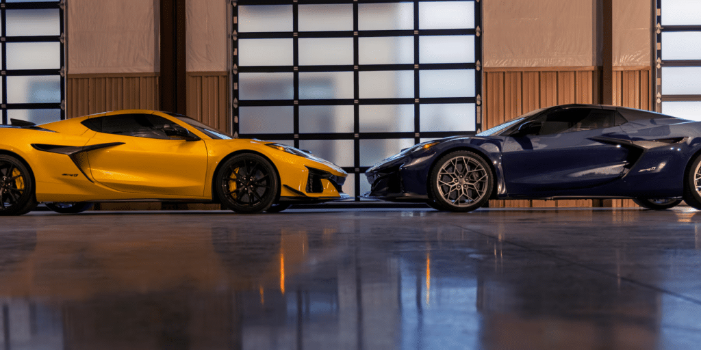 Imagen de dos Chevrolet Corvette ZR1 2025, uno en color amarillo brillante y el otro en azul profundo. Ambos coches están estacionados dentro de un edificio con grandes ventanas que permiten la entrada de luz natural, reflejándose en el suelo pulido. La imagen destaca el diseño elegante y agresivo de los coches, con faros distintivos y grandes tomas de aire en la parte delantera.