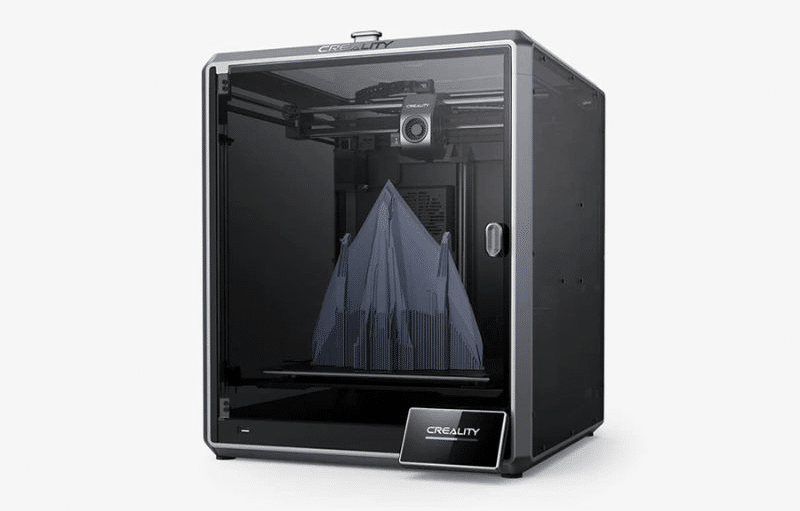 Impresora 3D Creality con una carcasa transparente y un marco negro. Dentro de la impresora, hay un objeto en proceso de impresión que parece una pirámide con capas intrincadas. La marca ‘Creality’ es visible en la parte inferior frontal de la impresora. Esta imagen muestra la tecnología moderna de impresión 3D capaz de crear objetos tridimensionales complejos capa por capa. piezas de coche impresora 3d