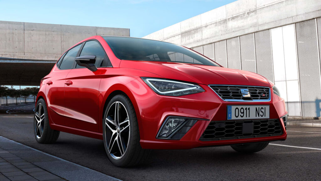 Un coche SEAT Ibiza rojo de 2017 está estacionado al aire libre con un cielo despejado de fondo. El coche está posicionado en un ángulo que resalta su diseño frontal y perfil. El vehículo presenta una parrilla distintiva, un diseño de faros afilados y llantas deportivas de aleación. La matrícula es ‘0911 NSI’.
