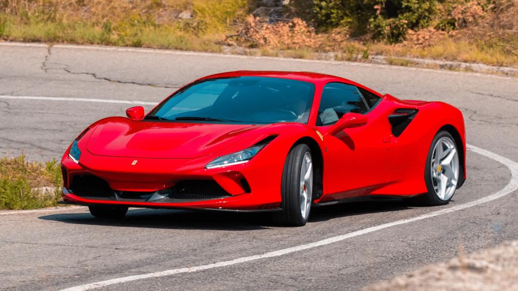 Imagen de un Ferrari F8 Tributo rojo en una carretera, girando ligeramente a la izquierda. El coche está en foco y el fondo está desenfocado, enfatizando el diseño y el movimiento del vehículo.