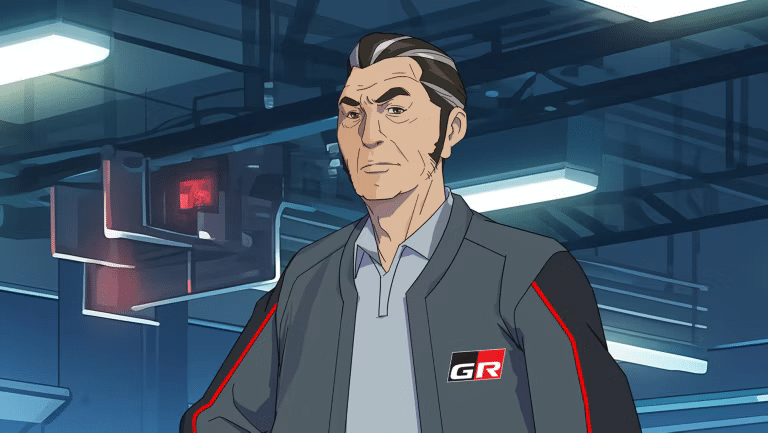 Un personaje del anime ‘GRIP, el anime de Toyota’ llamado Maestro Rogu. Está en lo que parece ser una sala de control de alta tecnología. Lleva un traje oscuro con detalles rojos y un distintivo que dice ‘GR’ en el lado izquierdo.