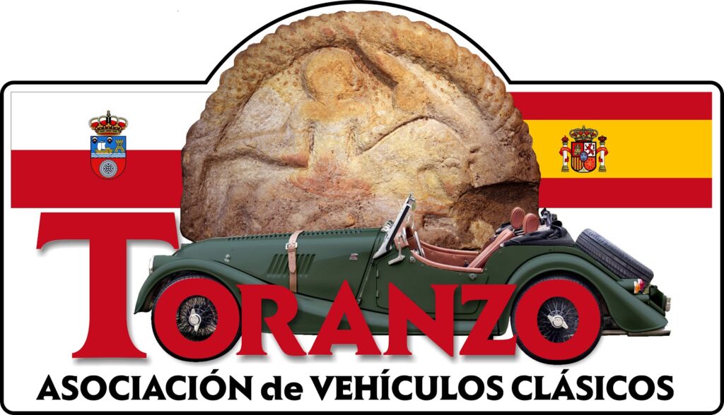 Logo de la Asociación de Vehículos Clásicos Toranzo. Presenta una imagen de un coche clásico color verde con detalles en cromo y asientos color crema, sobre un fondo que muestra una fotografía desvanecida de una rueda de carro antigua. Encima del coche, el texto “Toranzo” en letras grandes y rojas. La bandera de España se encuentra a ambos lados del texto, con un escudo pequeño a la izquierda y el escudo nacional de España a la derecha. Debajo del coche, el texto “ASOCIACIÓN DE VEHÍCULOS CLÁSICOS” en letras mayúsculas negras sobre fondo blanco.