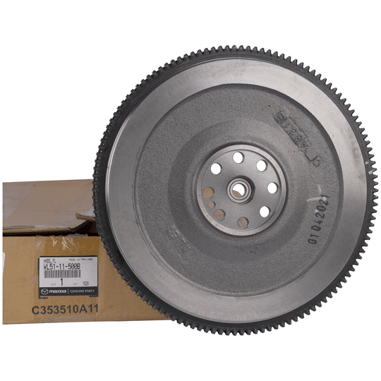 Imagen de un volante motor monomasa. Este componente automotriz, utilizado en el sistema de embrague del motor, se muestra nuevo y colocado sobre una caja de cartón, lo que sugiere que es una imagen de producto para venta o reemplazo.