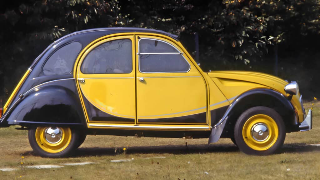 Gracias por la corrección. Aquí tienes: La imagen muestra un Citroën 2CV Charleston clásico, un modelo vintage conocido por su diseño distintivo y su importancia histórica en el mundo automotriz. El coche tiene un esquema de colores de dos tonos con una carrocería amarilla y guardabarros negros. El coche está estacionado en una zona de césped con árboles en el fondo. Este modelo es interesante debido a su diseño único e icónico y su papel en la historia automotriz europea como un vehículo asequible y práctico en la posguerra.
