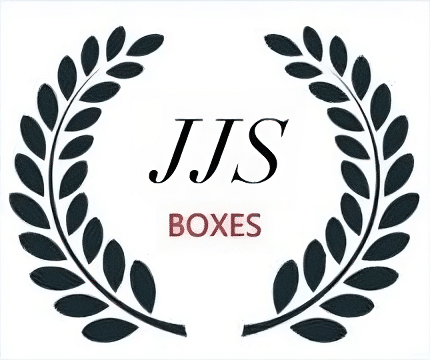 La imagen muestra un logotipo que consiste en dos ramas de laurel de color negro formando un círculo abierto con las puntas hacia arriba. Dentro del círculo, hay letras grandes y estilizadas “JJS” en el centro, y debajo en una fuente más pequeña la palabra “BOXES”. El fondo es blanco y no hay otros elementos visibles.