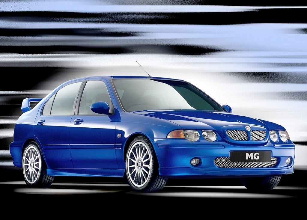 La imagen muestra un coche MG ZS 180 azul, específicamente un modelo sedán deportivo. El coche está posicionado contra un fondo dinámico con rayas negras, blancas y grises, dando una sensación de velocidad y movimiento. El coche presenta un diseño elegante con una parrilla frontal prominente, llantas de aleación y un alerón trasero. El logotipo de MG es visible en la parrilla frontal y en la matrícula.