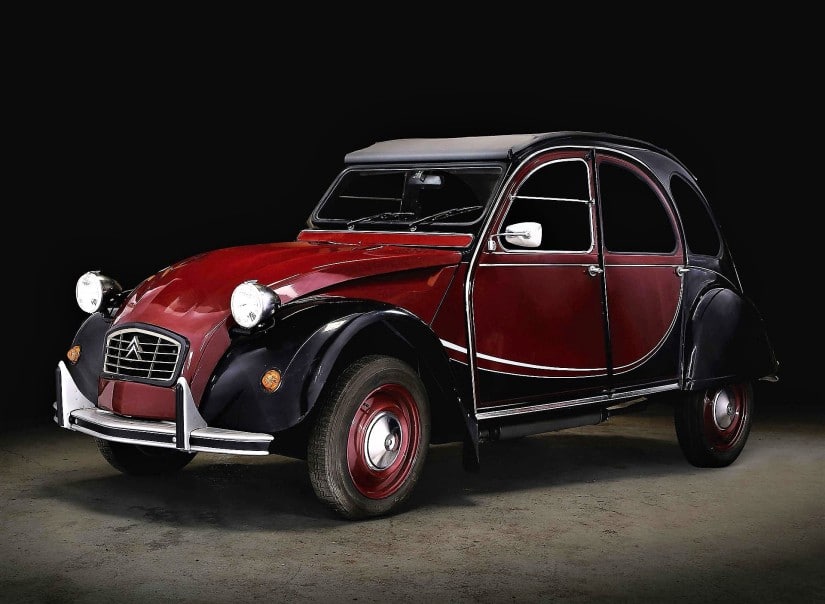La imagen muestra un Citroën 2CV Charleston clásico, un modelo vintage conocido por su diseño distintivo y su importancia histórica en el mundo automotriz. El coche tiene un esquema de colores de dos tonos con una carrocería roja y negra, faros redondeados y un techo de lona. El Citroën 2CV es interesante y relevante debido a su estatus icónico en la historia del automóvil, representando el diseño y la ingeniería de coches europeos de la posguerra.
