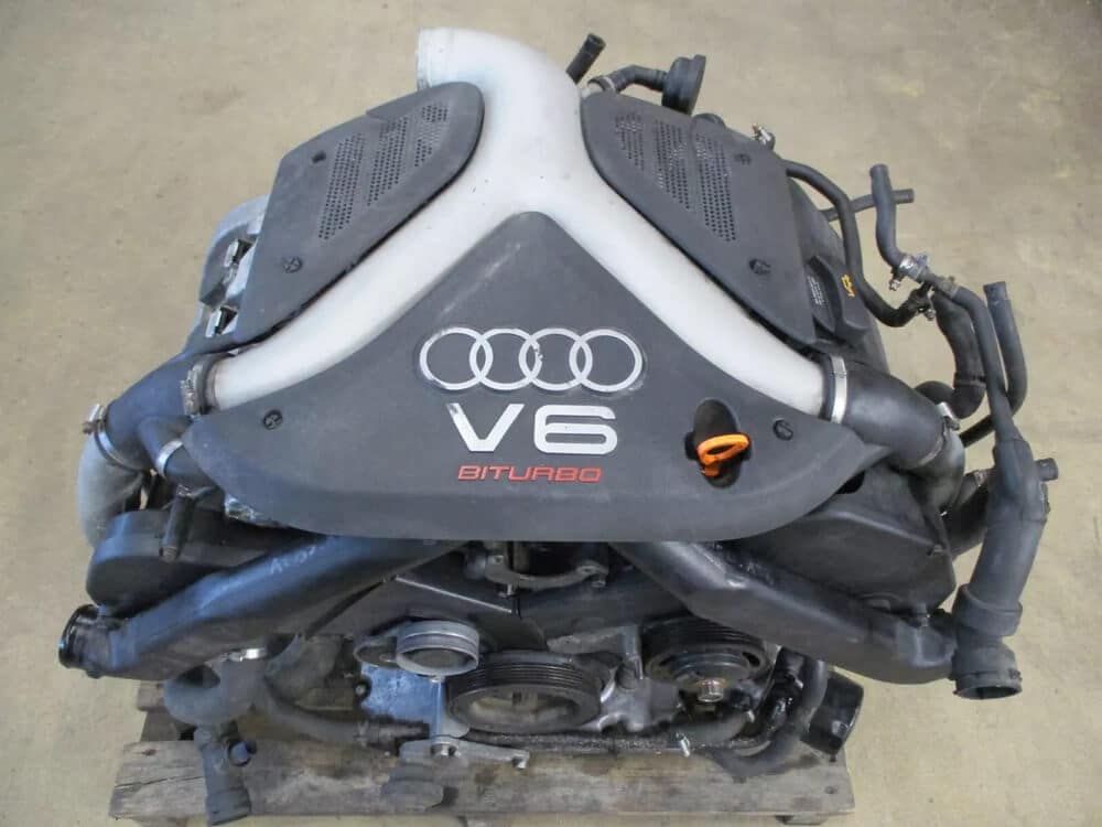 La imagen muestra un motor V6 Biturbo de un Audi S4 B5. El motor está claramente marcado con el logotipo de Audi y el texto 'V6 BITURBO'. Este motor es interesante y relevante porque representa un tren motriz de alto rendimiento utilizado en el Audi S4 B5, conocido por su potencia e ingeniería. La imagen destaca el diseño y los componentes del motor, que son cruciales para los entusiastas y profesionales del automovilismo.