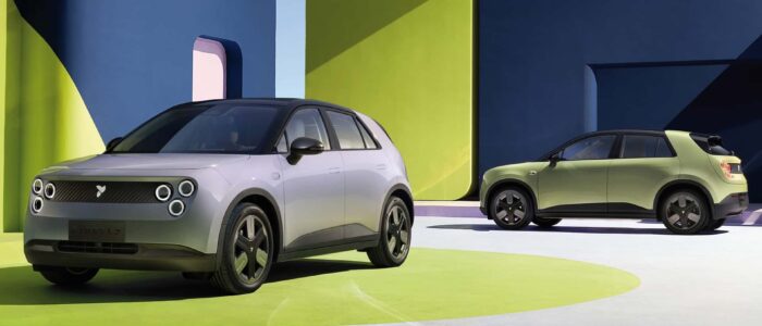 Dos vehículos eléctricos NIO Firefly en un entorno estilizado y colorido. El vehículo en primer plano es plateado con un diseño elegante y faros circulares, mientras que el vehículo en el fondo es verde. El escenario presenta grandes formas geométricas en colores vibrantes, creando un fondo futurista y artístico. Esta imagen es interesante y relevante ya que destaca el diseño y el atractivo estético de los vehículos eléctricos, enfatizando la innovación y la sostenibilidad en la tecnología automotriz.