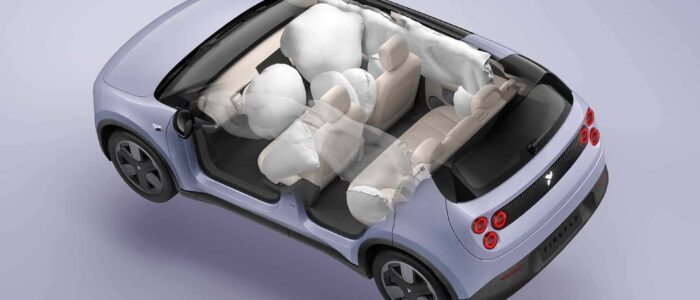 Vista superior de un NIO Firefly con todos sus airbags desplegados. El coche parece ser un modelo compacto con un exterior púrpura claro y un interior beige. Los airbags son visibles en las posiciones frontal, lateral y de cortina, indicando un sistema de airbags completo diseñado para proteger a los ocupantes en caso de colisión. Esta imagen es interesante y relevante ya que destaca las características de seguridad del vehículo, mostrando el nivel de protección proporcionado por los airbags.