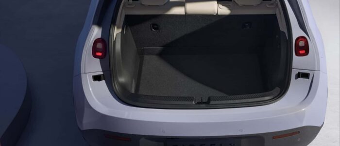 El maletero abierto de un NIO Firefly, un coche eléctrico. El maletero está vacío y tiene un interior limpio y espacioso con alfombrado oscuro. Los asientos traseros son visibles, y las luces traseras del coche están encendidas. El nombre de la marca del coche, 'NIO Firefly', es visible en el parachoques trasero. Esta imagen es interesante y relevante ya que destaca el espacio de carga y las características de diseño del maletero del coche, lo cual puede ser importante para los posibles compradores que evalúan la practicidad y la capacidad de almacenamiento del vehículo.