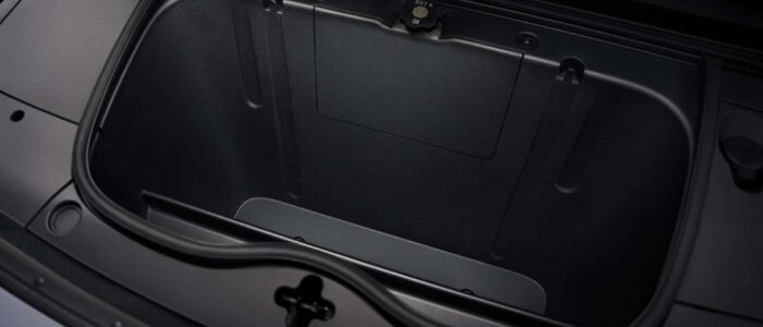 El maletero delantero (frunk) de un NIO Firefly, un coche eléctrico. El frunk está vacío y tiene un interior liso y negro con un mecanismo de cierre visible en la parte superior. Esta característica es interesante y relevante porque destaca el espacio de almacenamiento adicional disponible en los vehículos eléctricos, que típicamente no tienen un motor en la parte delantera, permitiendo una mayor capacidad de carga.