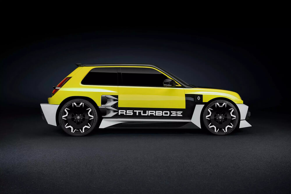 La imagen muestra una vista lateral de un coche compacto deportivo con un diseño distintivo y agresivo. El coche está pintado en un color amarillo brillante con detalles en negro y blanco. El texto 'R5 TURBO 3E' se muestra de manera prominente en el lateral del coche, indicando el modelo. El coche cuenta con grandes ruedas negras intrincadas con detalles en blanco y un kit de carrocería ancho que incluye guardabarros ensanchados y elementos aerodinámicos. El diseño general sugiere un vehículo de alto rendimiento, probablemente inspirado en o rindiendo homenaje a los coches de rally clásicos. Esta imagen es interesante y relevante porque muestra una interpretación moderna de un modelo de coche clásico, combinando elementos de diseño retro con estilo y tecnología contemporáneos.