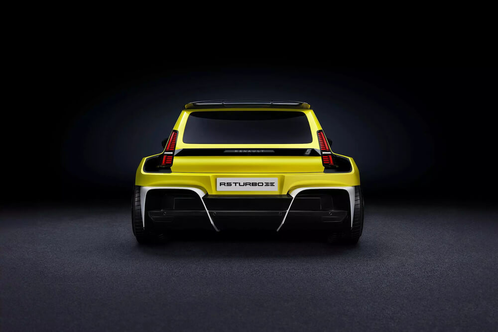 "La imagen muestra la vista trasera de un Renault 5 Turbo 3E amarillo. El coche tiene un diseño deportivo y agresivo con guardabarros traseros anchos, un difusor trasero prominente y luces traseras verticales distintivas. En la zona de la matrícula se puede leer el texto 'R5 TURBO 3E'. Esta imagen es interesante y relevante porque muestra la reinterpretación moderna del clásico Renault 5 Turbo, destacando su diseño actualizado y características de rendimiento.