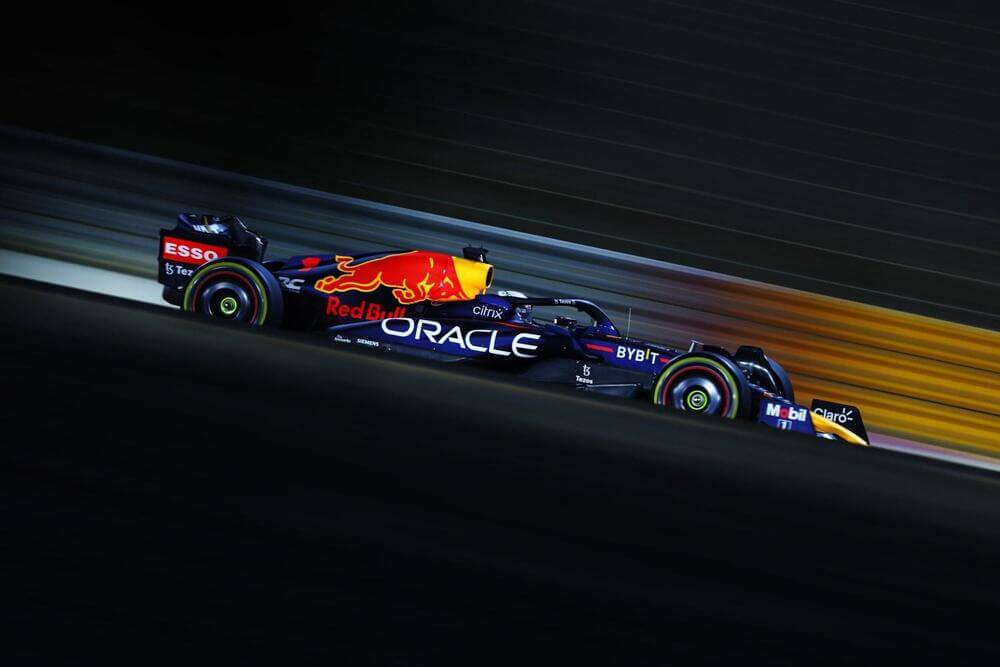 Un coche de Fórmula 1 de Red Bull Racing en movimiento, con logotipos de Oracle, Red Bull y otros patrocinadores como Esso, Bybit y Mobil. El coche está capturado a alta velocidad, con un fondo borroso que indica movimiento. La imagen destaca la naturaleza de alta velocidad de las carreras de Fórmula 1 y la importancia del patrocinio en el deporte.