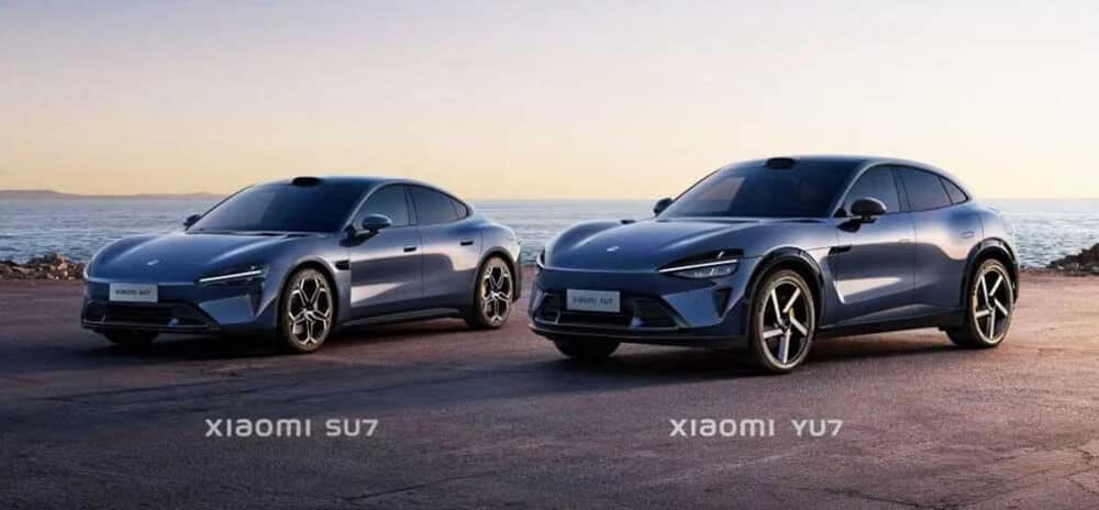 La imagen muestra dos vehículos eléctricos de Xiaomi, etiquetados como "Xiaomi SU7" y "Xiaomi YU7." Ambos coches están estacionados en una carretera costera con el océano y un atardecer de fondo. El Xiaomi SU7 está a la izquierda y el Xiaomi YU7 a la derecha. Los vehículos tienen diseños elegantes y modernos con formas aerodinámicas y llantas de aleación estilizadas. Esta imagen es interesante y relevante ya que muestra la entrada de Xiaomi en el mercado de vehículos eléctricos, destacando sus avances en diseño y tecnología automotriz.