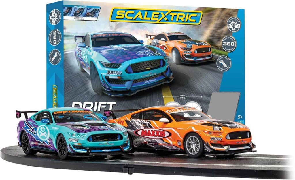 La imagen muestra un set de carreras Scalextric Drift, que incluye dos coches modelo y una sección de la pista. La caja en el fondo presenta una imagen de los dos coches en acción, uno azul y el otro naranja. El set está diseñado para derrapes, como indica la palabra 'DRIFT' en la caja. La caja también menciona que el set es adecuado para mayores de 5 años e incluye acción de derrape de 360 grados. Esta imagen es interesante y relevante para aquellos interesados en las carreras de coches modelo y la colección, ya que muestra un tipo específico de set de carreras diseñado para derrapes.