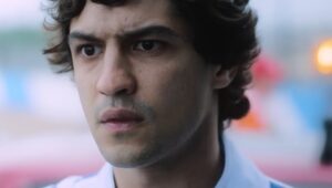 La imagen muestra un primer plano del rostro de Ayrton Senna, el legendario piloto de Fórmula 1. Senna tiene una expresión seria y concentrada, con el fondo desenfocado que sugiere un entorno de carreras. La iluminación resalta sus rasgos faciales, capturando la intensidad y el enfoque que lo caracterizaban. Esta imagen es interesante y relevante porque destaca el legado de Senna en el automovilismo y la naturaleza dramática de su carrera.