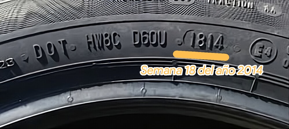 "Primer plano de la pared lateral de un neumático con varias marcas. La marca resaltada '1814' indica que el neumático fue fabricado en la semana 18 del año 2014. Esta información es relevante para determinar la antigüedad del neumático, lo cual es importante para la seguridad y el rendimiento.