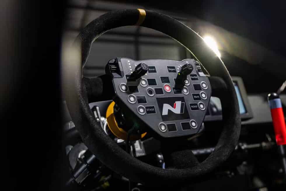"Imagen del volante de un Hyundai RN24. El volante está equipado con varios botones y interruptores, etiquetados con funciones como 'Accel,' 'Regen,' 'PowerBal,' 'Stage,' 'Road,' y 'Mark.' En el centro del volante hay un logotipo con la letra 'N' y un punto rojo. Este volante es parte del diseño avanzado del Hyundai RN24, destacando sus características de alta tecnología y funcionalidad.