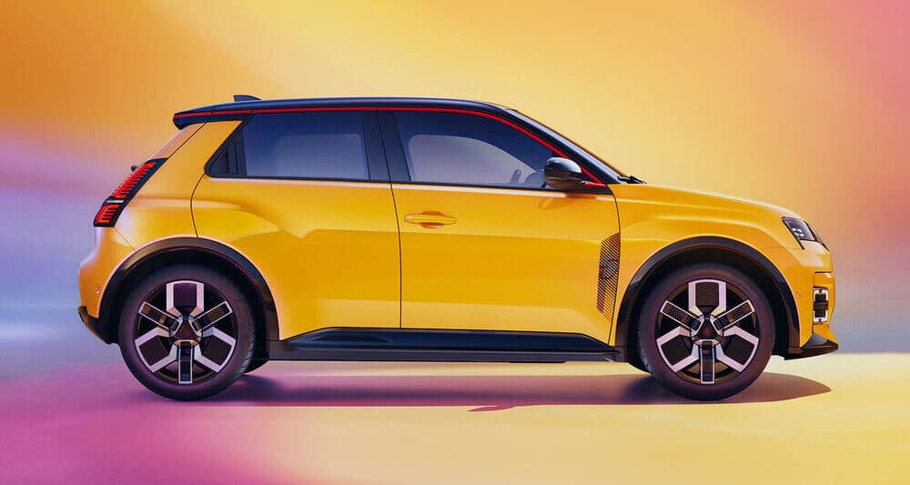 La imagen muestra la vista lateral de un Renault 5 E-Tech amarillo con un diseño moderno y elegante. El coche presenta acentos negros distintivos, incluyendo el techo, los espejos laterales y el borde inferior de la carrocería. Las ruedas tienen un patrón geométrico único, y el coche tiene una apariencia deportiva con líneas afiladas y una postura ligeramente agresiva. El fondo es un degradado de colores cálidos, que pasa del amarillo al rosa, lo que añade un toque vibrante y dinámico a la imagen. Esta imagen es interesante porque destaca el diseño y el atractivo estético del vehículo, mostrando sus características contemporáneas y elegantes.