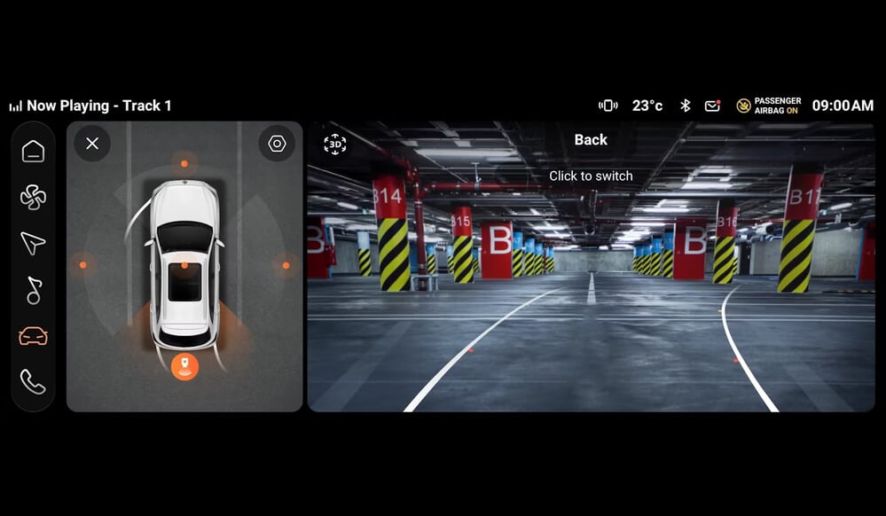 La imagen muestra el panel de instrumentos de un MG ZS Hybrid+. La pantalla está dividida en dos secciones principales. A la izquierda, hay una vista superior del coche con los sensores de estacionamiento activados, indicando la proximidad de objetos alrededor del vehículo. A la derecha, se muestra la imagen de la cámara trasera de un garaje con varios espacios de estacionamiento etiquetados con "B" y números como B14, B15 y B16. La pantalla también muestra varios iconos e información, incluyendo la pista actual en reproducción ("Now Playing - Track 1"), la temperatura (23°C), la conectividad Bluetooth, el estado del airbag del pasajero ("PASSENGER AIRBAG ON") y la hora (09:00 AM). En el lado izquierdo también hay iconos para el hogar, control de clima, navegación, configuración del coche y teléfono. El texto "Click to switch" y "Back" son visibles en el lado derecho de la pantalla.