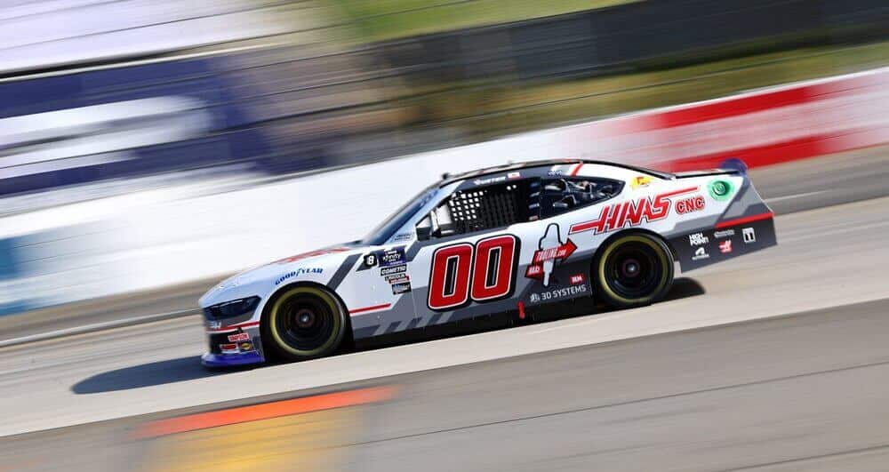 CALENDARIO NASCAR 2025: Coche de carreras NASCAR con el número 00, patrocinado por Haas CNC y Goodyear, en una pista de carreras, capturado en movimiento con un fondo borroso que indica alta velocidad.