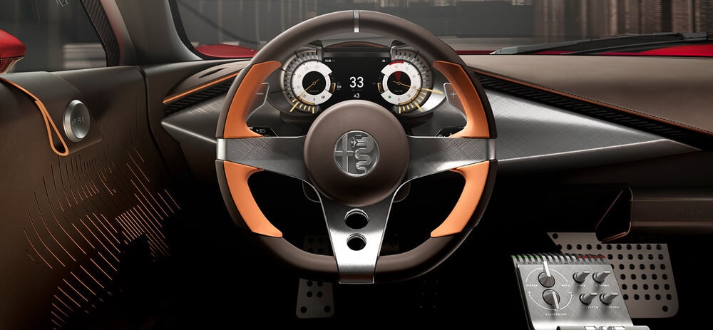 Imagen del interior de un auto deportivo Alfa Romeo 33 Stradale, enfocándose en el volante y el tablero. El volante tiene un diseño moderno y deportivo con una combinación de materiales metálicos y de cuero, y presenta el logotipo de Alfa Romeo en el centro. El tablero muestra dos indicadores circulares con una pantalla digital en el centro que muestra los números '33' y 'A3'. El diseño interior incluye acentos marrones y naranjas, con una estética futurista y elegante. Los pedales y los botones de control son visibles en la parte inferior derecha, añadiendo un toque de alta tecnología al interior del auto.