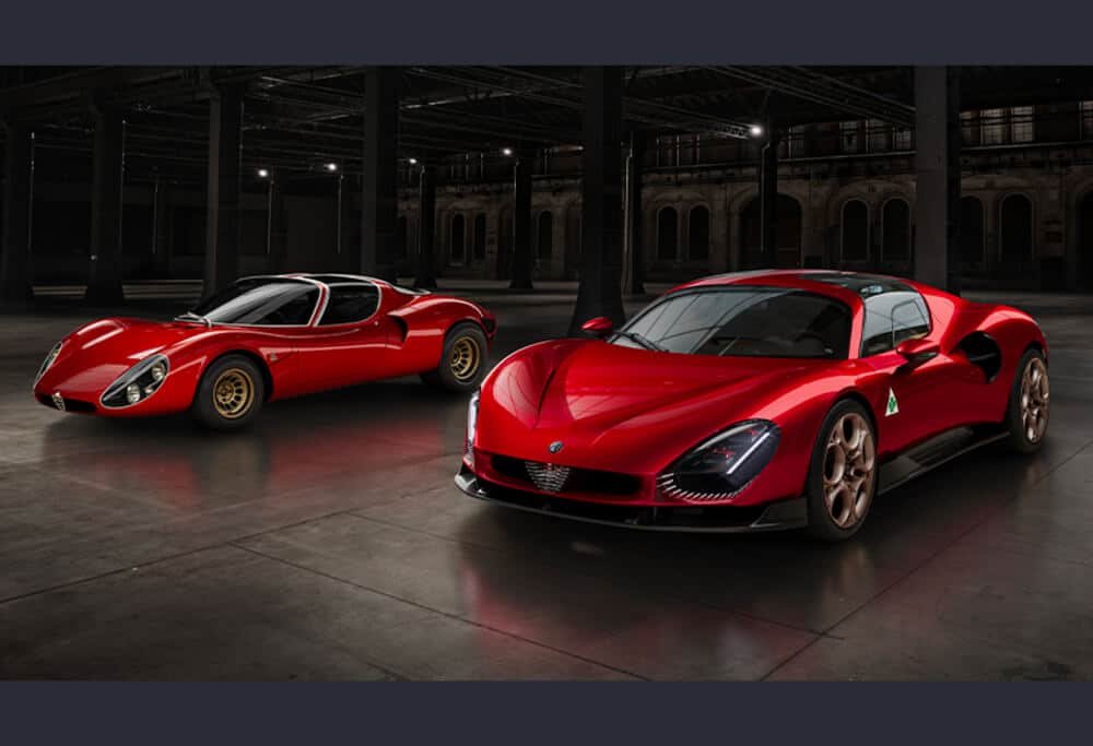 Imagen de dos autos deportivos rojos en un edificio industrial con poca luz. El auto a la izquierda es un modelo clásico con un diseño redondeado y llantas doradas, mientras que el auto a la derecha es una versión moderna con líneas aerodinámicas y llantas de bronce. Ambos autos tienen un perfil bajo y están posicionados para resaltar sus características de diseño.