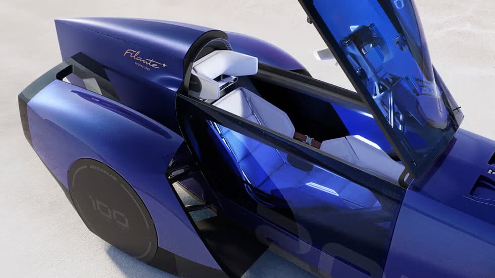 El Renault Filante 2025 es un coche futurista con un diseño aerodinámico y elegante, predominantemente de color azul. El vehículo tiene una puerta de ala de gaviota abierta, revelando un interior moderno y minimalista con asientos blancos. En el lateral del coche se puede ver el texto 'Filante' y 'since 1954'. La rueda del coche tiene el texto 'MICHELIN' y '100', indicando la marca de los neumáticos y posiblemente una referencia a una edición especial o modelo. Esta imagen es interesante y relevante ya que muestra un diseño automotriz innovador y tecnología avanzada, reflejando la dirección futura de la fabricación de automóviles y la estética del diseño.