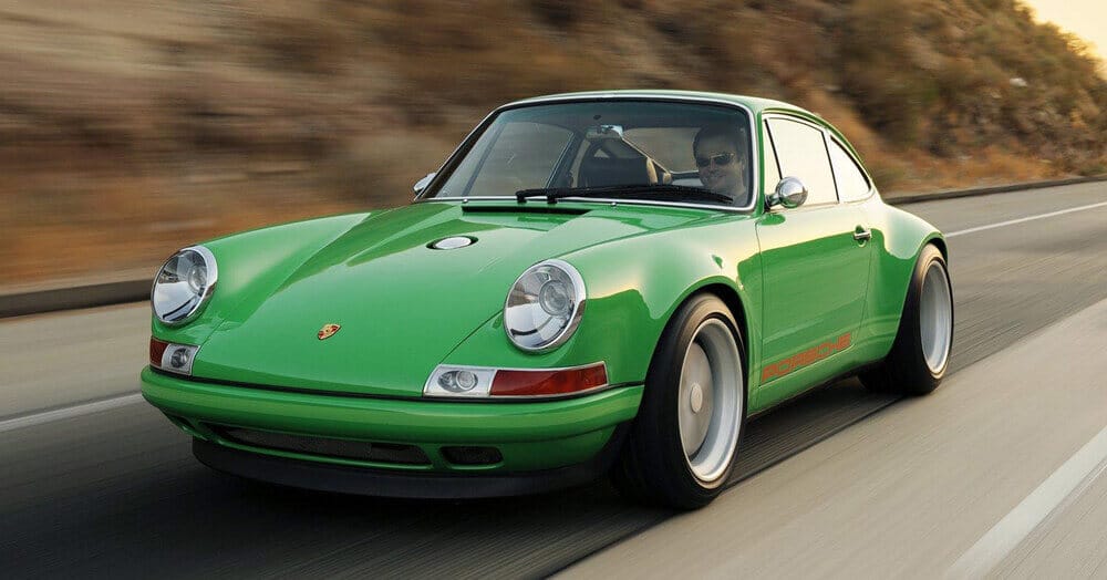 "Imagen de un Porsche 911 verde clásico en movimiento por una carretera. El coche destaca por su diseño aerodinámico, faros redondos característicos y neumáticos anchos. En el capó se ve el emblema de Porsche, y la palabra 'Porsche' está escrita en rojo en el lateral. El fondo muestra un paisaje borroso, sugiriendo velocidad y dinamismo.
