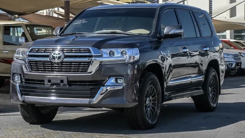 "Un Toyota Land Cruiser 2015 de color gris oscuro, expuesto en un concesionario de coches en Dubái. El coche luce detalles cromados y está en excelentes condiciones. Esta imagen es relevante para el tema 'importar coches de Dubái a España', mostrando un vehículo robusto y de alta demanda, ideal para los interesados en importación y compra de coches.