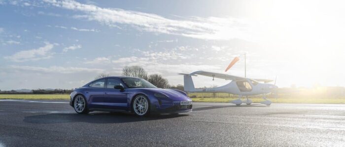 El Porsche Taycan de color morado estacionado al lado de la avioneta similar a una Cessna.
