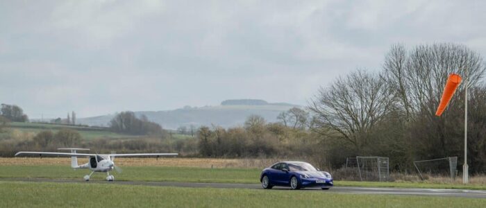 El Porsche Taycan púrpura acelera y el avión blanco despega.