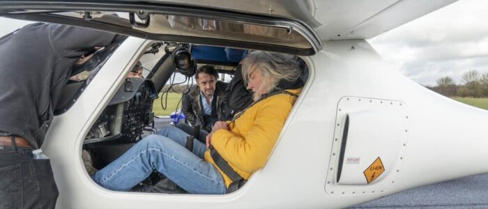 James May sentado dentro de la avioneta. Richard Hammond mira desde afuera.