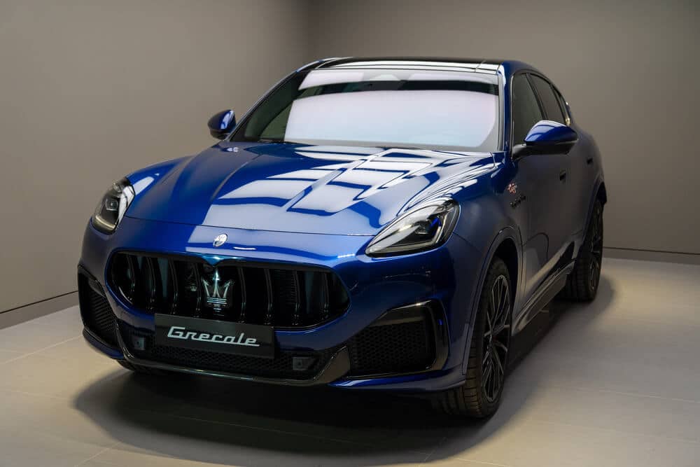 Un Maserati Grecale SUV azul exhibido en un showroom. El automóvil destaca por su diseño elegante con una parrilla frontal prominente, el icónico logo del tridente de Maserati y unos faros sofisticados. En la parte delantera se aprecia una placa con el nombre 'Grecale'.