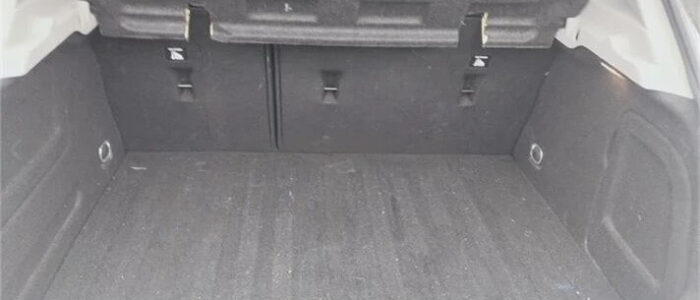 La imagen muestra el maletero de un Opel Astra de segunda mano en Zaragoza. El maletero está abierto, revelando un área de carga espaciosa con un suelo y laterales alfombrados en color oscuro. Los asientos traseros son visibles y parecen ser abatibles para ampliar el espacio de carga. No hay objetos visibles en el maletero, lo que indica que está vacío y limpio. Esta imagen es ficticia y se utiliza para un estudio que demuestra las habilidades de marketing de Miana.